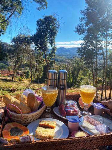 a picnic with bread and two glasses of orange juice at Refúgio Physis Suítes in Monte Verde