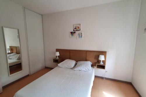 une chambre avec un lit blanc et un miroir dans l'établissement Maison de vacances proche du canal du midi et de la mer, à Colombiers