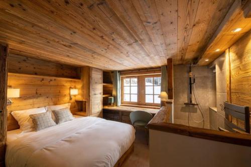美贝尔Chalet Le Plaigny - golf de Méribel的带一张大床和木质天花板的卧室
