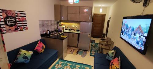 a living room with a blue couch and a kitchen at شاليه فندقى مكيف بالكامل - جراند هيلز الساحل الشمالى Grand Hills North Coast - Families only Z25 in Dawwār ‘Abd Allāh