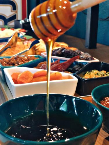 a person pouring honey into a bowl of food at Green Rooms in Kutaisi