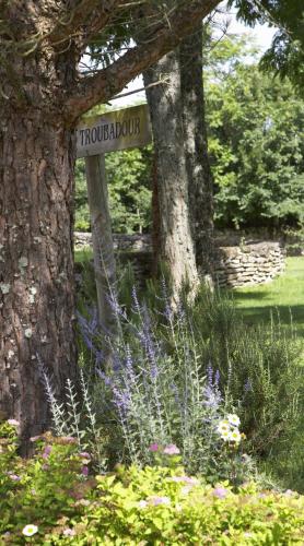 a sign in a garden next to two trees at Hôtel Le Troubadour à Rocamadour in Rocamadour