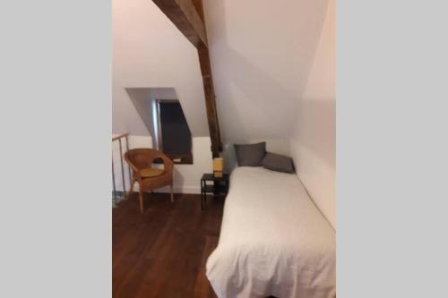 um quarto com uma cama branca e uma cadeira em Maison de pêcheur près du port em Étaples