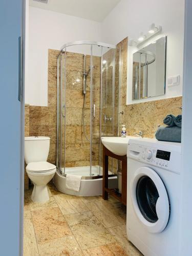 ein Bad mit einer Dusche, einem WC und einer Waschmaschine in der Unterkunft Apartament Walczaka nr 16 MIEJSCE PARKINGOWE in Gorzów Wielkopolski