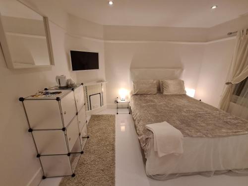 a white bedroom with a large bed and a television at The White House in Waltham Cross