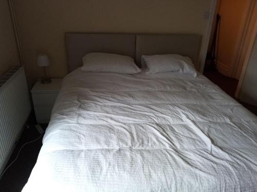 a large white bed with two pillows on it at Puffin Holiday Apartments in Bridlington