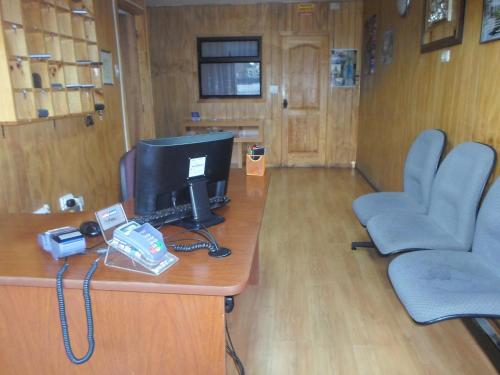 a office with a desk with a computer and two chairs at Hostal Fx in Puerto Montt