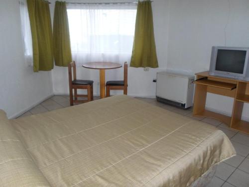 Schlafzimmer mit einem Bett, einem Tisch und einem TV in der Unterkunft Apart Hotel Fx in Puerto Montt