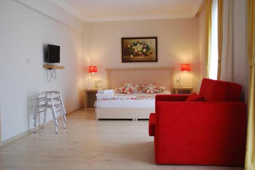 a bedroom with a white bed and a red couch at Melaike Hotel in Foça