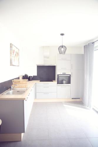 une cuisine blanche avec des armoires blanches et un évier dans l'établissement Maison neuve à 350m de la plage La casa Sovaïna, à Cléder