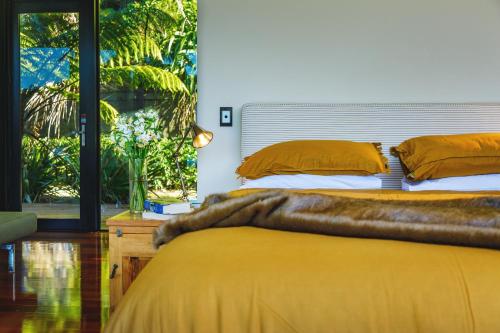 a bedroom with a large bed with orange pillows at Waterfall Bay Glass House in Picton