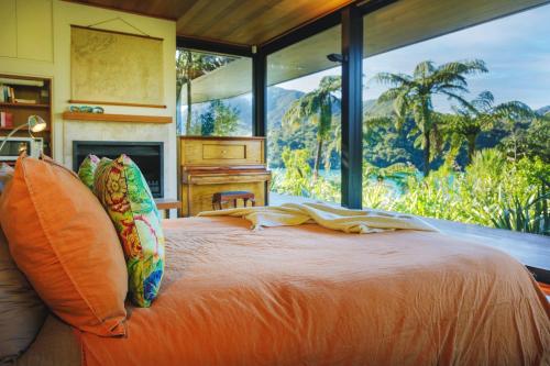 una camera da letto con un letto e una grande finestra di Waterfall Bay Glass House a Picton