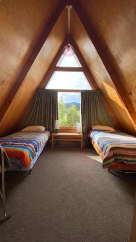 a attic room with two beds and a window at 9 Chalet Cres in Hanmer Springs