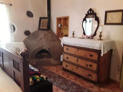 a bedroom with a fireplace and a dresser with a mirror at Ecoartejeda CAVE HOUSE in Tejeda