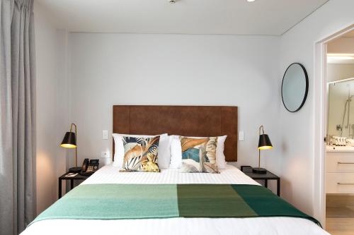 a bedroom with a large bed and two lamps at Quest Mount Eden in Auckland