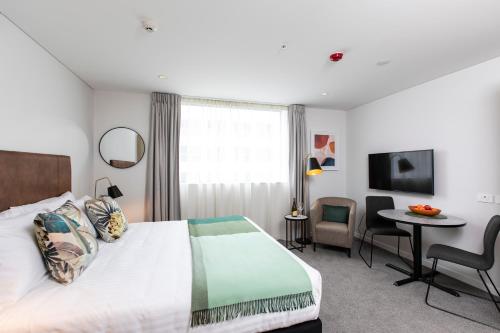 pokój hotelowy z łóżkiem, stołem i krzesłami w obiekcie Quest Mount Eden w Auckland