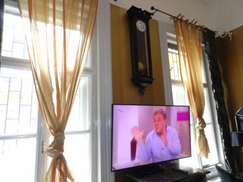 a flat screen tv in a room with a clock at Boudoir Budapest Apartment in Budapest