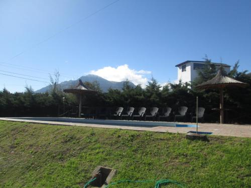 a pool with chairs and umbrellas on the grass at Pa-kuas del Uritorco in Capilla del Monte