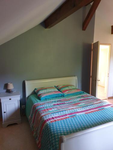 a bedroom with a bed with a colorful comforter at Au Grés du Vent in Ruy