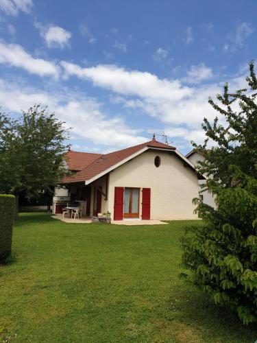 a house with a red door and a grass yard at Au Grés du Vent in Ruy