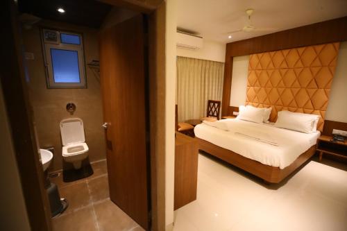 a bedroom with a bed and a bathroom with a toilet at Hotel Dream Residency in Navi Mumbai