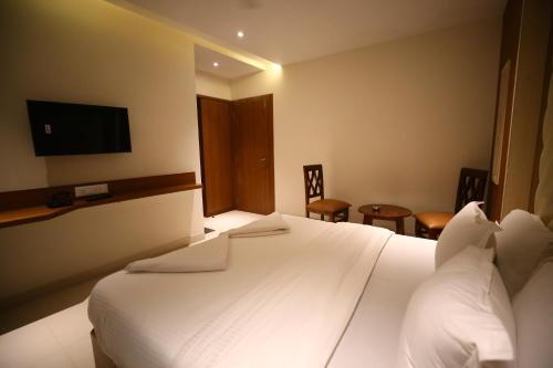 a hotel room with a white bed and a tv at Hotel Dream Residency in Navi Mumbai
