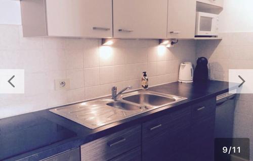 a kitchen with a stainless steel sink and white cabinets at Studio Ostend Living in Ostend