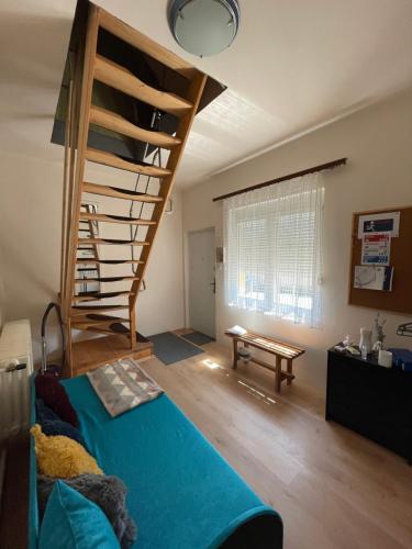 a living room with a blue bed and a spiral staircase at Mira Kuckó in Öreglak