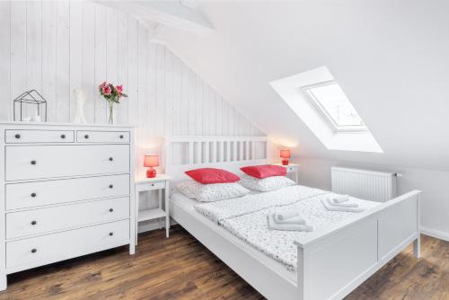 a white bedroom with a white bed and red pillows at Penzion Belle Donne in Znojmo