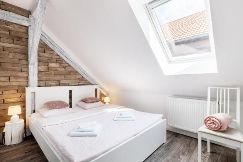a white bedroom with a bed and a window at Penzion Belle Donne in Znojmo