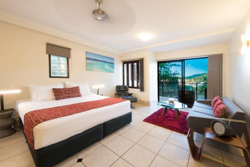 1 dormitorio con cama, sofá y ventana en at Waterfront Whitsunday Retreat - Adults Only, en Airlie Beach