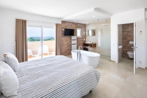 um quarto com uma cama e uma banheira e uma casa de banho em Stunning villa, heated pool, pool bar, sea views em Loulé