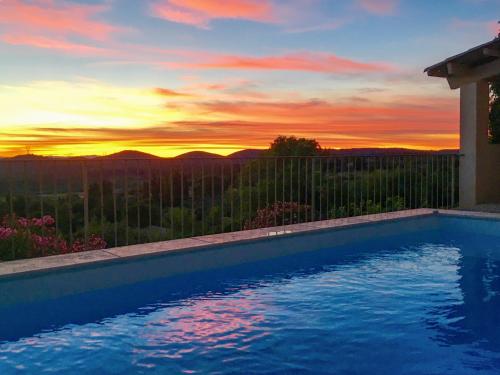 uma piscina com um pôr-do-sol ao fundo em Petit Paradis Bellevue em Montpezat
