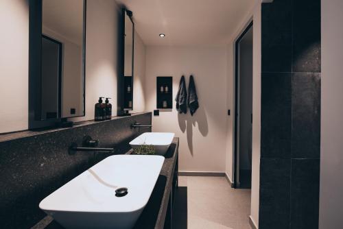 a bathroom with two white sinks and a black counter at More Meni Residence & Suites in Tigaki