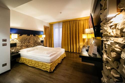 a hotel room with a bed and a stone wall at Boutique Exclusive B&B in Trento