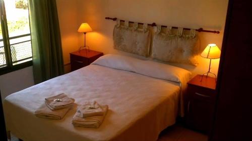 Un dormitorio con una cama blanca con toallas. en Pinares de Colon en Colón