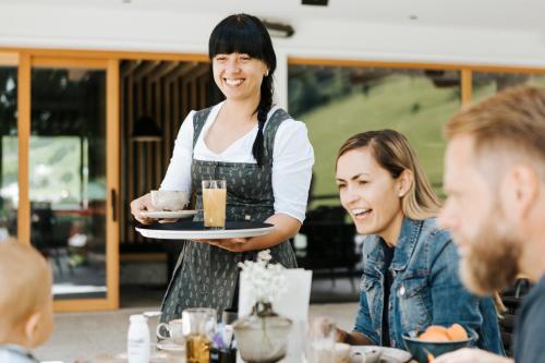 a waitress holding a plate of food in a restaurant at Hotel Thurnerhof in Saalbach Hinterglemm