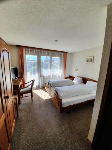 1 dormitorio con 2 camas, escritorio y ventana en Hotel Central, en Agarn