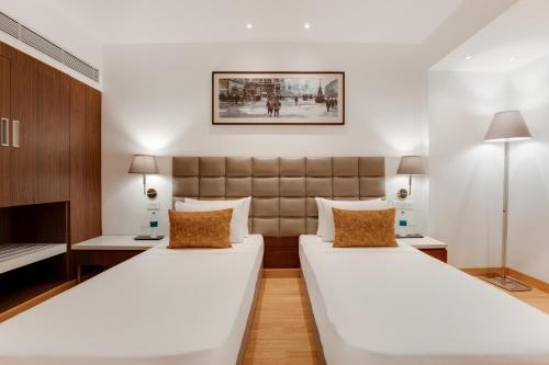 2 camas en una habitación con 2 lámparas en Hotel Aketa Rajpur Road Dehradun, Dehradun, en Dehradun