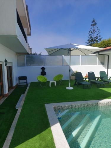 a backyard with a pool and an umbrella and chairs at Lavra Beach House in Lavra