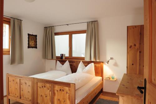 a bedroom with a wooden bed with white pillows at Almrausch Apartments in Sesto