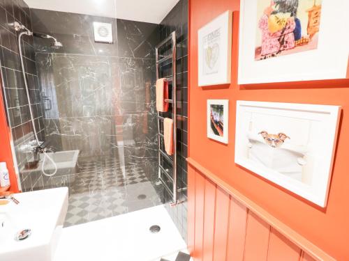 an orange bathroom with a shower and a sink at Prospect Cottage in Malvern Wells