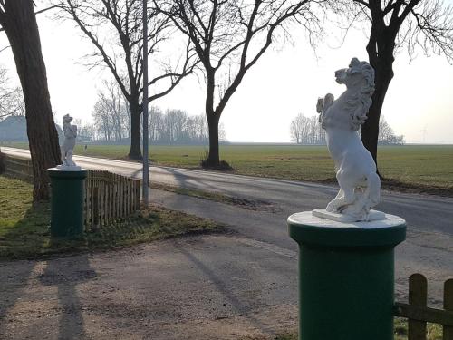 BundeにあるSteinhaus Hofの公園の柱に立つ犬像