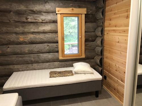 a bed in a wooden room with a window at Kojamopirtit in Kolari