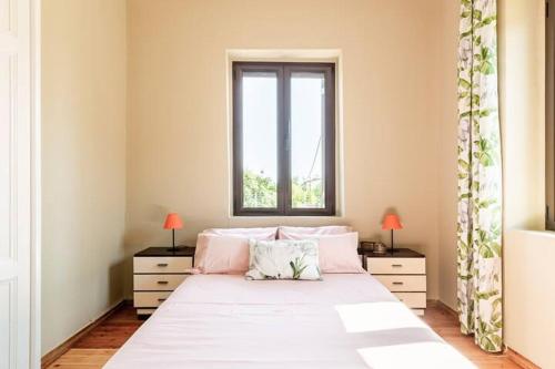 a bedroom with a large white bed with a window at Mansion of 120 m2, with high ceilings and big yard in Evangelístria
