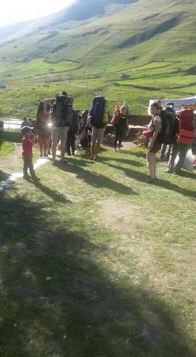 a group of people walking up a hill with luggage at Chvibiani Guesthouse & Bar in Ushguli