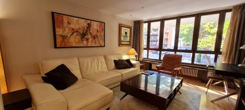 ein Wohnzimmer mit einem weißen Sofa und einem Glastisch in der Unterkunft APARTAMENTO CARMELITAS in Salamanca