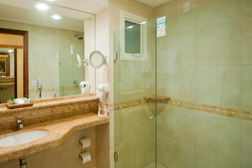 a bathroom with a glass shower and a sink at Pontalmar Praia Hotel in Natal