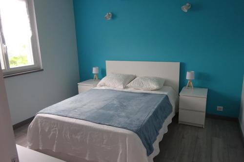 a bedroom with a bed with a blue wall at Les figères - Les gites de Pierregras in Vals-les-Bains