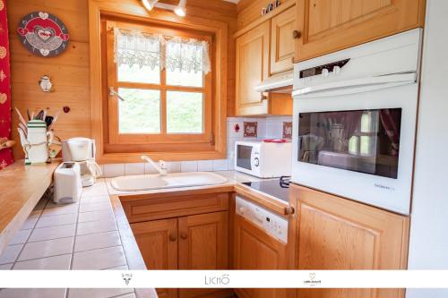 een keuken met houten kasten en een witte wastafel bij Sur Le Feug Appt 14 in Combloux